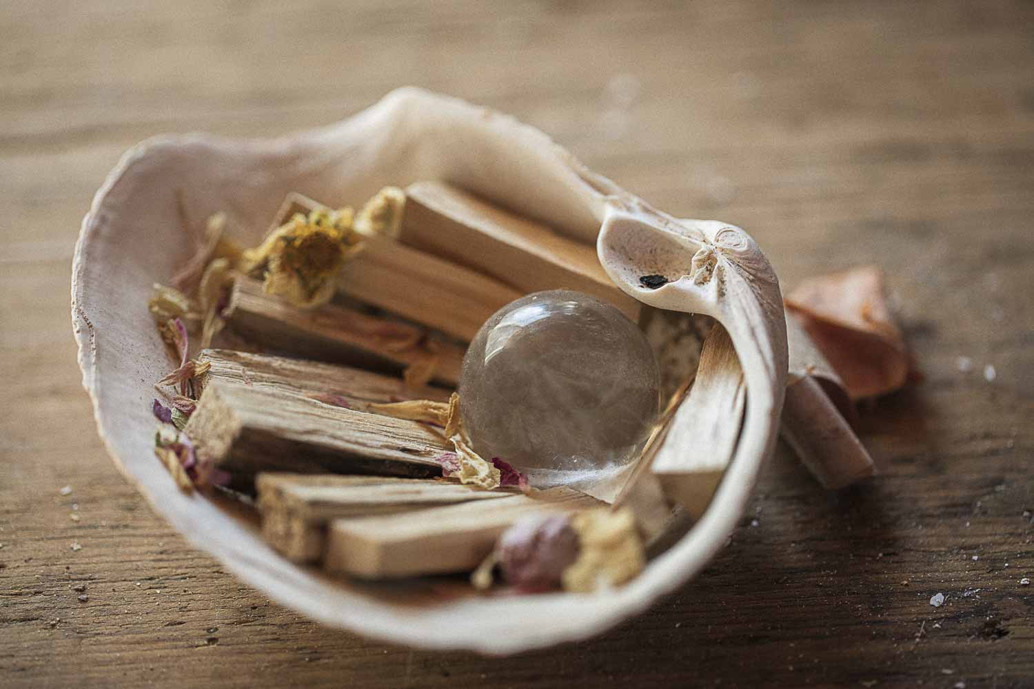 Shell burner dish with wooden sticks, and a crystal ball on a wooden surface