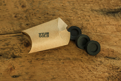 Black charcoal with Wylde Gold packaging on a wooden surface