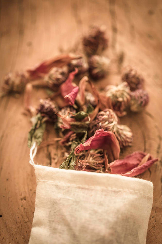 Herbal yoni steam blend with dried peonies, clover, and botanicals spilling from a cotton pouch on rustic wood background – Peony for Your Yoni by Wylde Gold