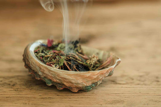 Fairy Dust Smudge Incense burning in a shell on a wooden surface