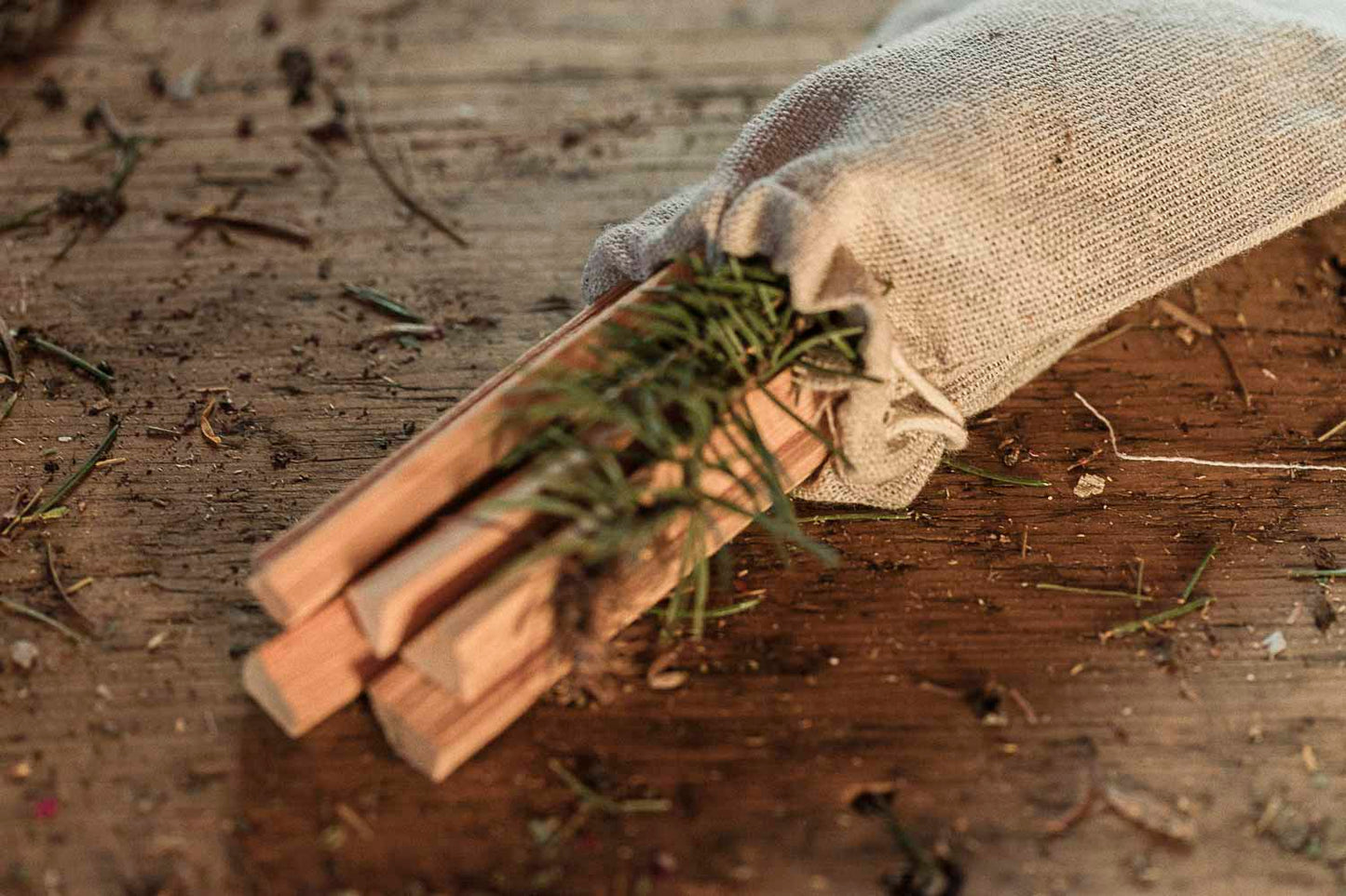 Wooden smudge ritual sticks with a small branch in a drawstring pouch on a wooden surface