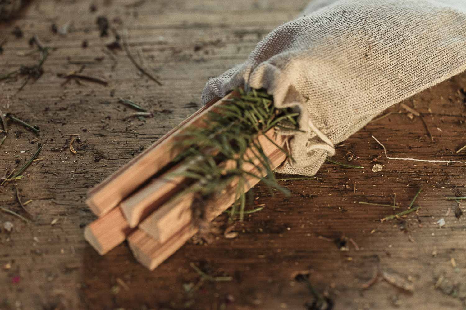 Wooden smudge ritual sticks with a small branch in a drawstring pouch on a wooden surface