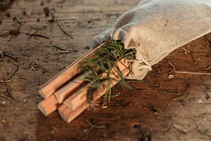 Wooden smudge ritual sticks with a small branch in a drawstring pouch on a wooden surface