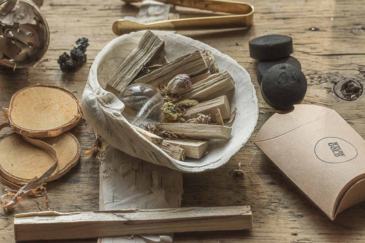 Birch elements in a bowl on a wooden surface with a box labeled 'WYLDE GOLD'.