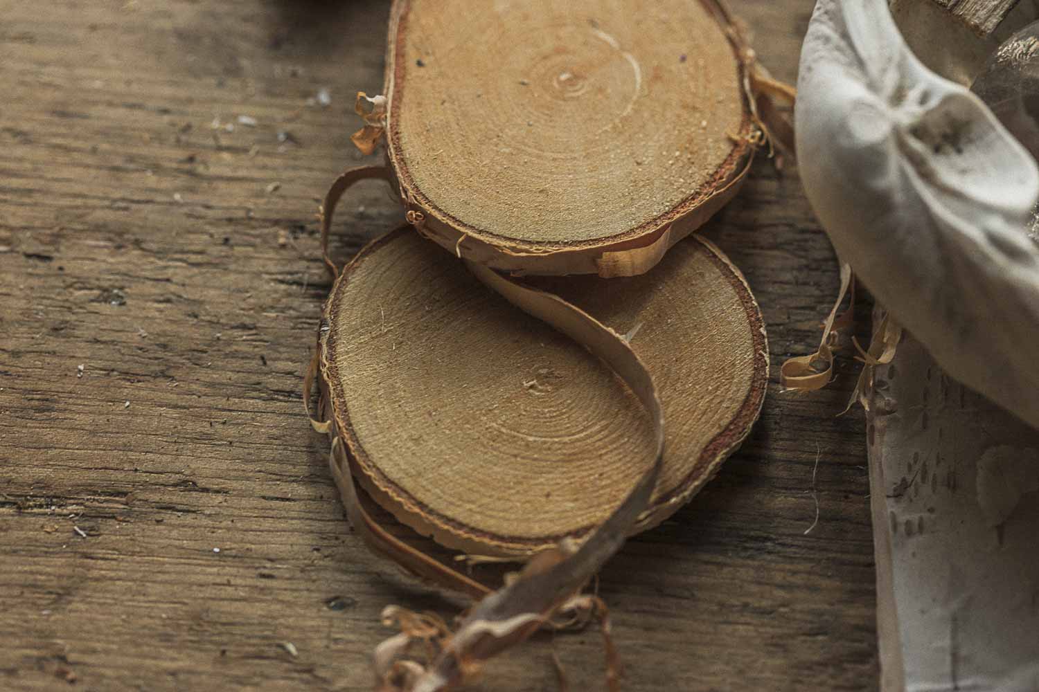 Wooden birch slices on a wooden surface with a hand holding a knife.
