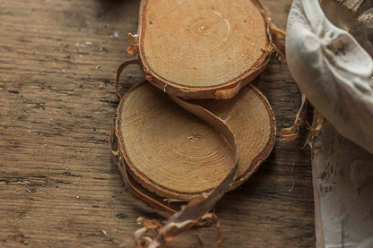 Wooden birch slices on a wooden surface with a hand holding a knife.