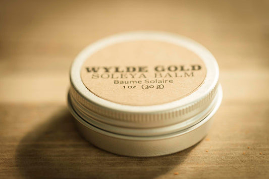 WYLDE GOLD Soleya Balm tin on rustic wood background – 1 oz sun balm with SPF, natural kraft label and metal lid.