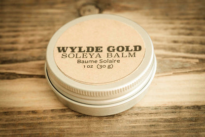 WYLDE GOLD Soleya Balm tin on rustic wood background – 1 oz sun balm with SPF, natural kraft label and metal lid.