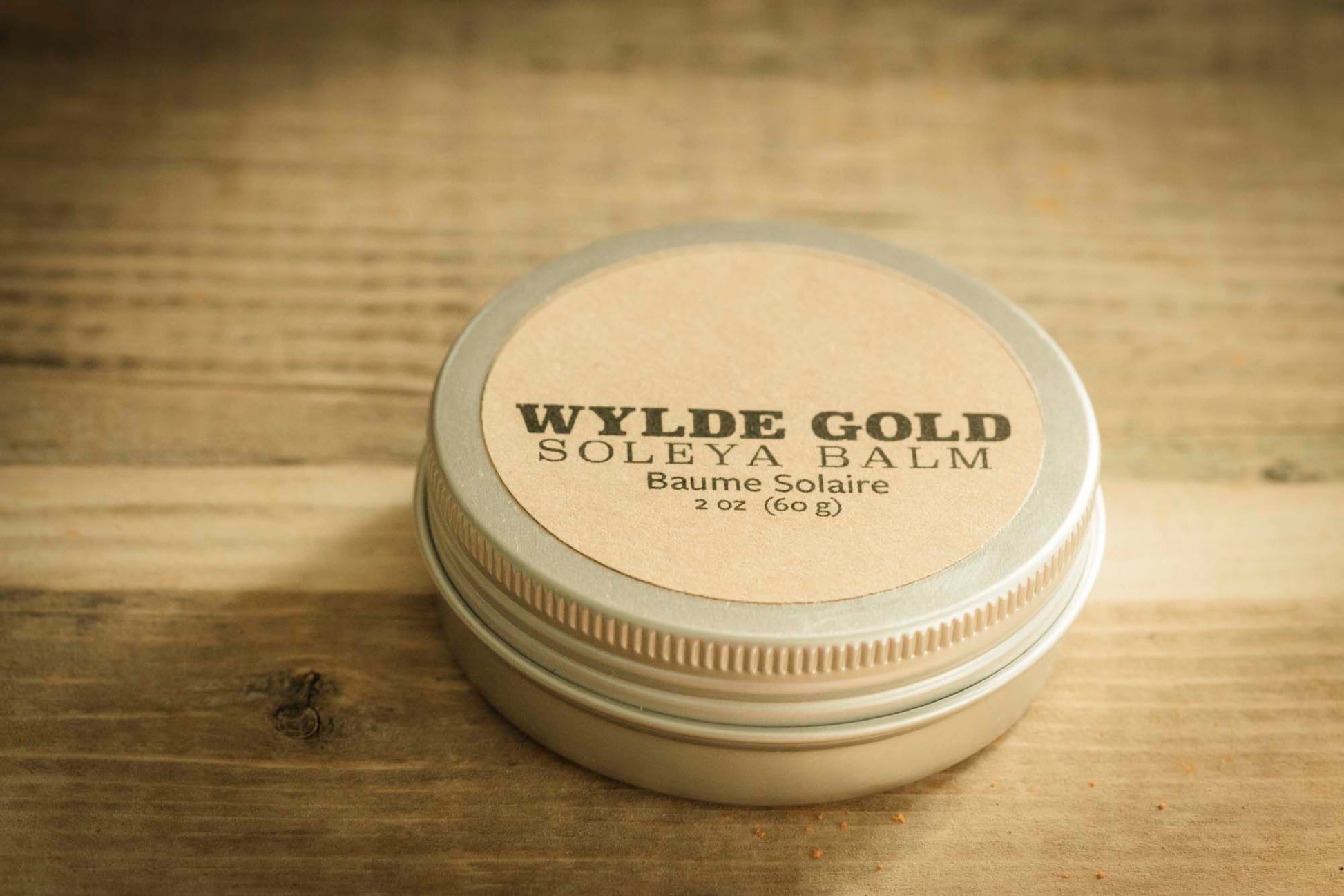WYLDE GOLD Soleya Sun sheild Tallow Balm (2 oz tin) displayed on rustic wood background