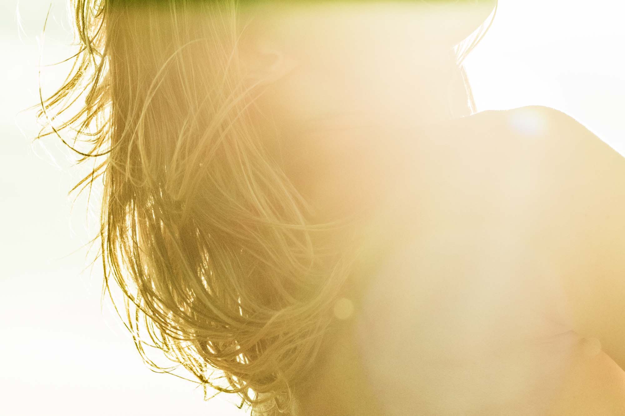 WYLDE GOLD | Sun-kissed hair in wind, profile of woman in golden light with eyes closed and serene expression