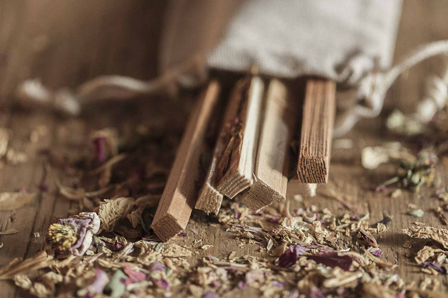 Wooden sticks in a bag of dried herbs on a wooden surface