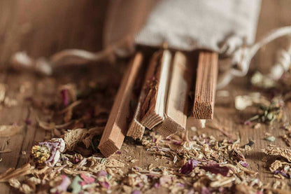 Wooden sticks in a bag of dried herbs on a wooden surface