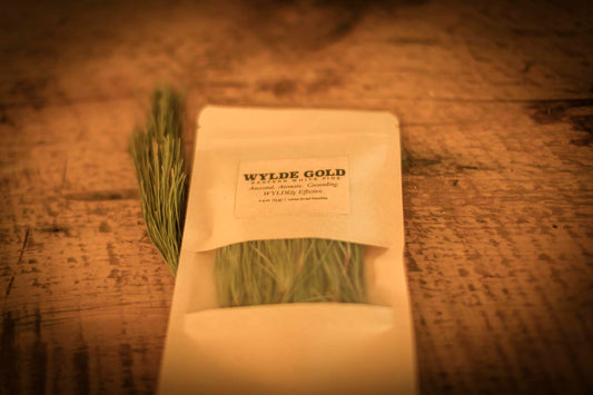 WYLDE GOLD Anoint the Pine — pouch of loose dried pine needles on rustic wood table with fresh pine sprig
