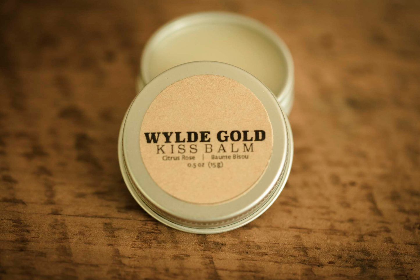 WYLDE GOLD Kiss Balm — Citrus Rose scented grass-fed tallow lip ritual in an open tin on wood