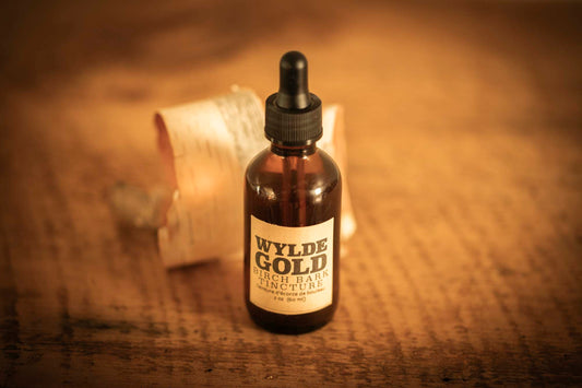 WYLDE GOLD Birch Bark Tincture — amber dropper bottle on rustic wood with birch bark