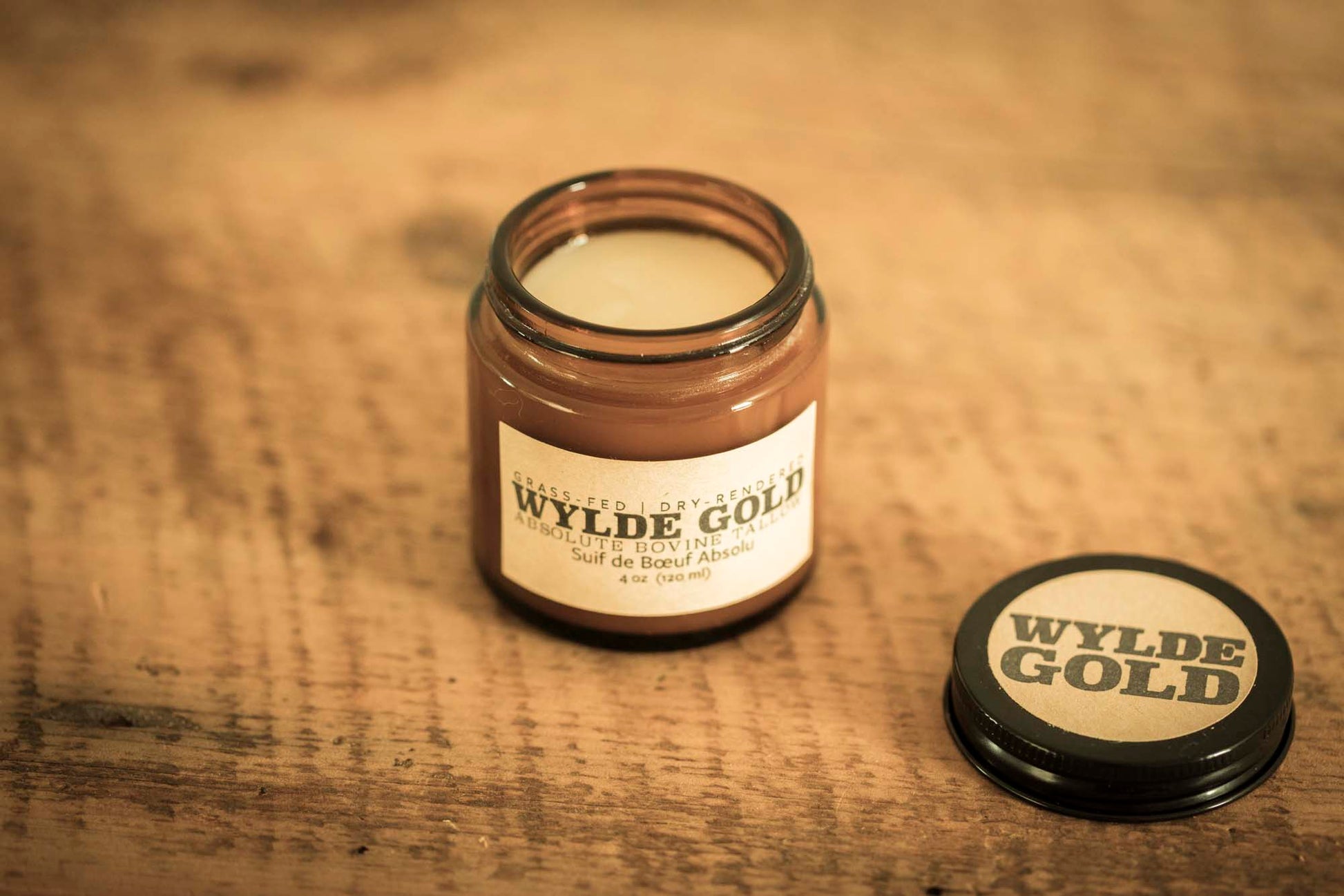WYLDE GOLD Absolute Balm — unscented grass-fed tallow ritual in an amber jar on rustic wood background