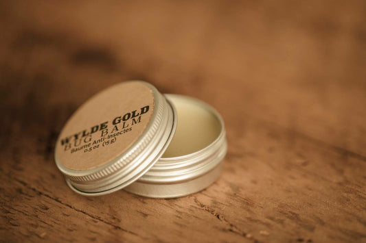 WYLDE GOLD Bug Balm —  grass-fed tallow insect repellent balm in an open tin on rustic wood