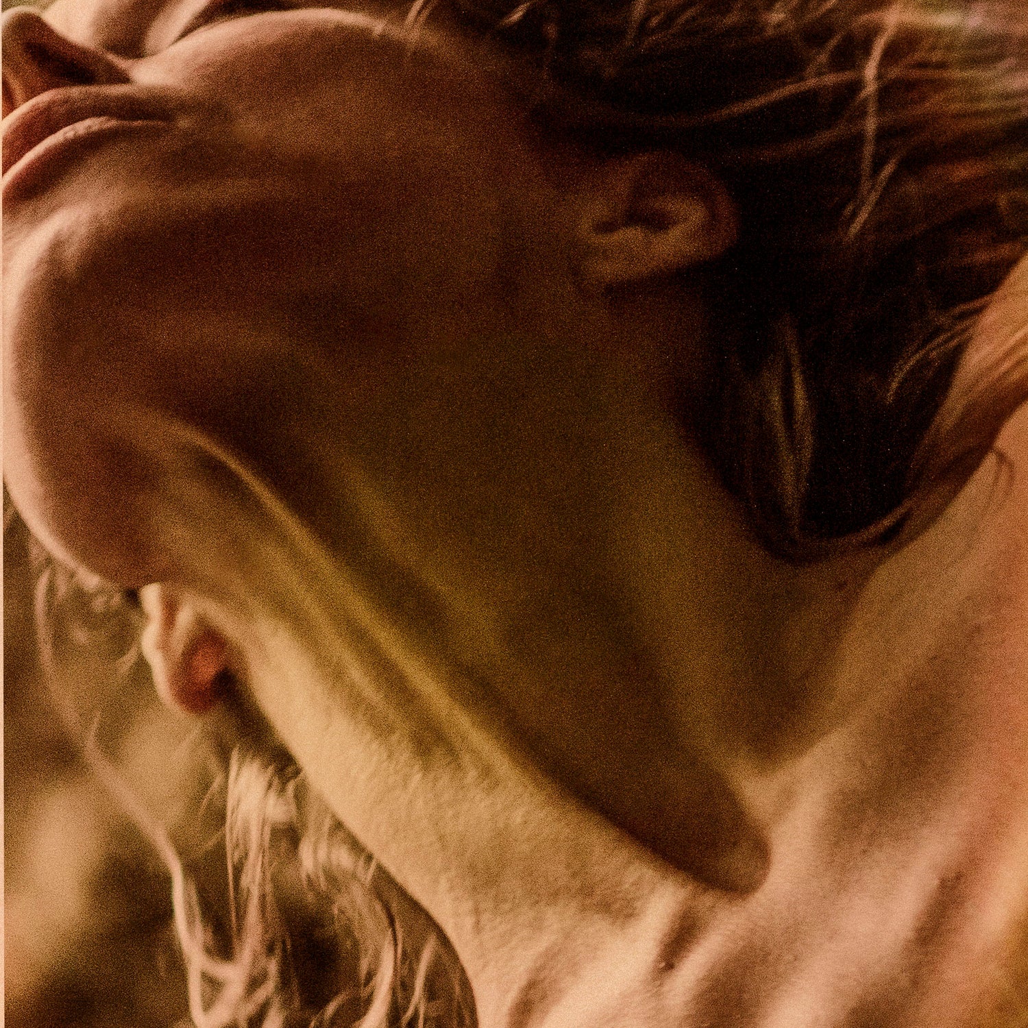 WYLDE GOLD Close-up of woman's neck and jawline in golden light, head tilted back in sensual motion and raw expression