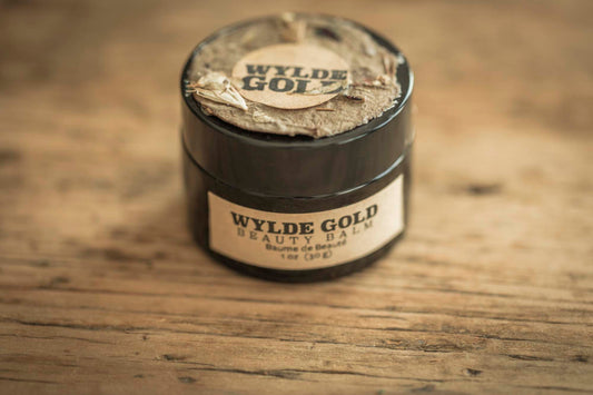 Beauty Balm crowned with wild bark and petals, resting on aged wood like a keepsake from the forest floor.